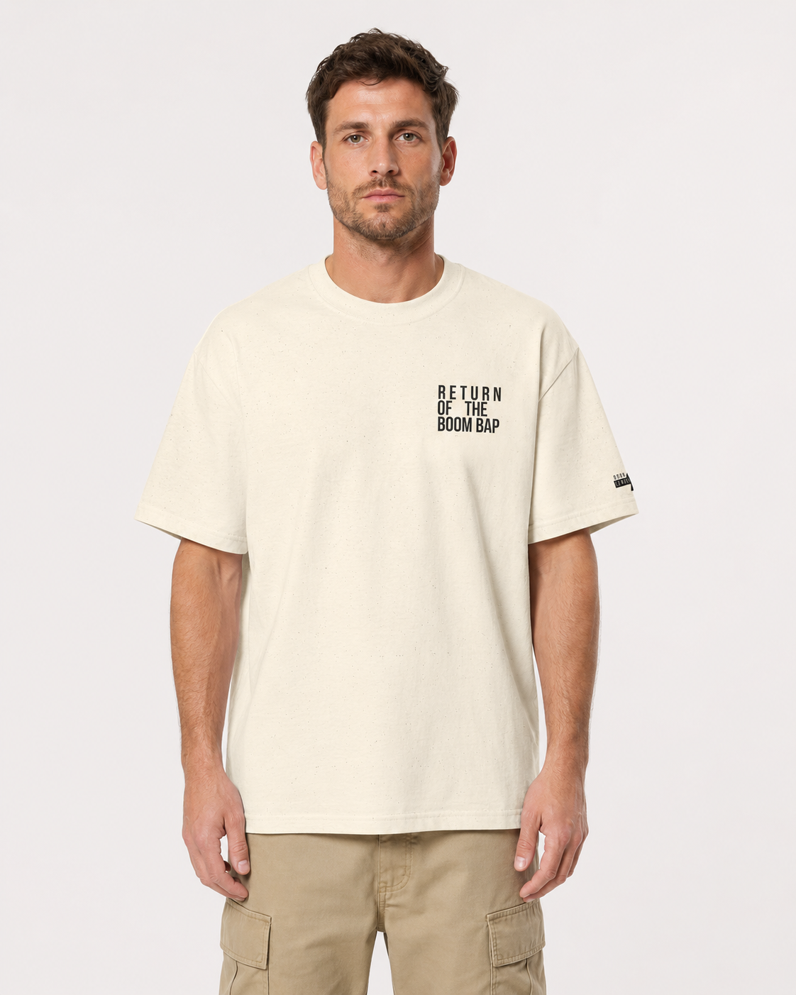 Front Natural A man wearing a cream-colored short-sleeve t-shirt with black text on the left chest reading 'RETURN OF THE BOOM GAP' and khaki cargo pants, standing against a light gray background.